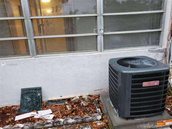 Exterior view of a building wall with windows and an air conditioning unit.