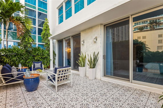 Front view of a modern building with large windows, patio furniture, and decorative tiles.