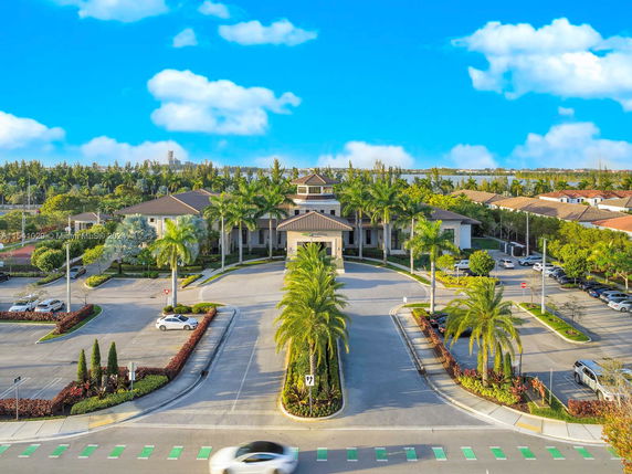 Front view of a large, single-story building with palm trees and a surrounding parking area.