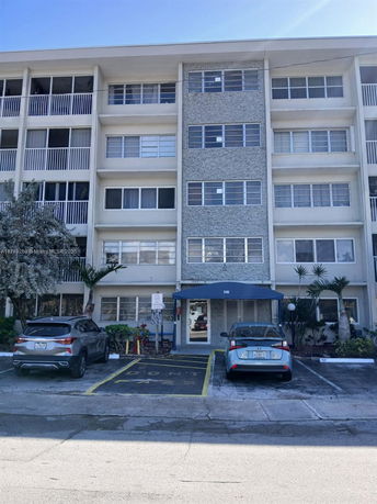 Front view of a multi-story residential building with parking area.