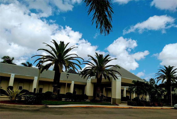 Front view of a building with palm trees and a tiled roof.