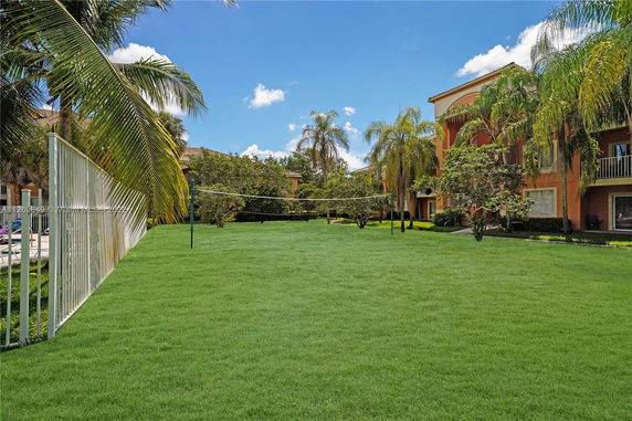 Outdoor grassy area with a volleyball net next to residential buildings.