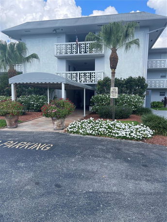 Front view of a multi-story building with balconies and a parking area.