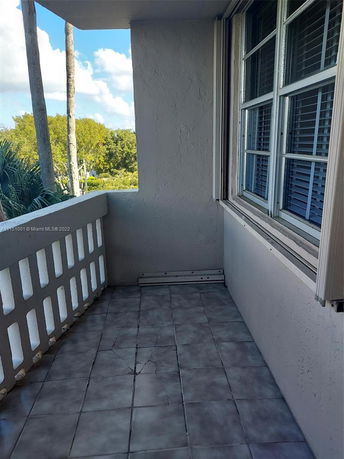 Balcony with tiled floor and view through the railing overlooking trees.