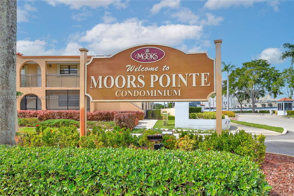 Front view of a multi-story condominium building with a welcome sign.