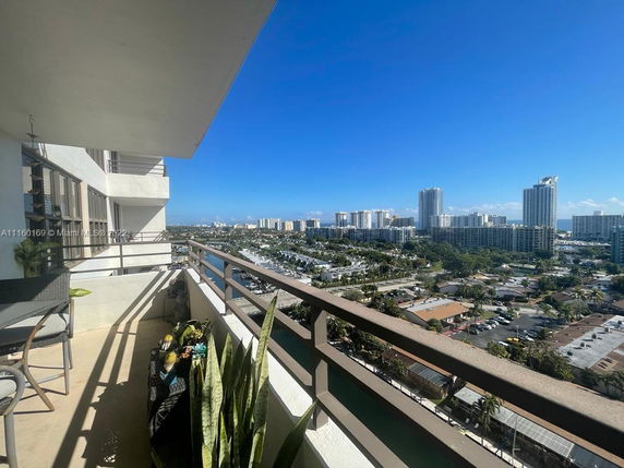 Balcony view from a high-rise building overlooking a cityscape with numerous buildings and clear sky.
