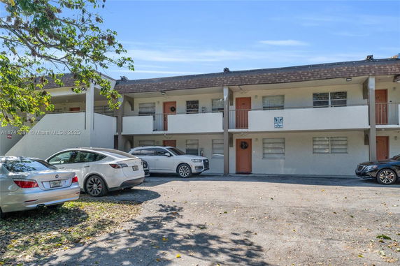 Outdoor parking area in front of a two-story building.