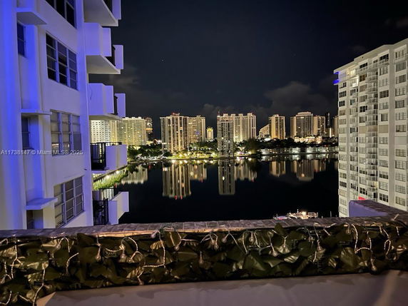 View of high-rise buildings at night with their reflections on a water body.