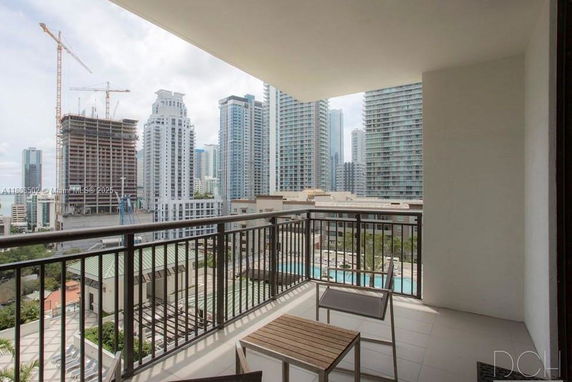 Panoramic view from a balcony overlooking a cityscape with tall buildings and cranes.
