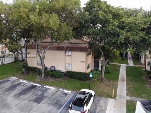 Aerial view of a residential building with parking spaces and surrounding trees.