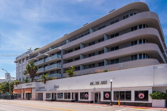 Front view of a multi-story building with retail shops on the ground floor.