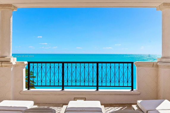 View from a balcony overlooking the ocean with clear blue water.