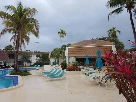 Outdoor swimming pool area with loungers and umbrellas.