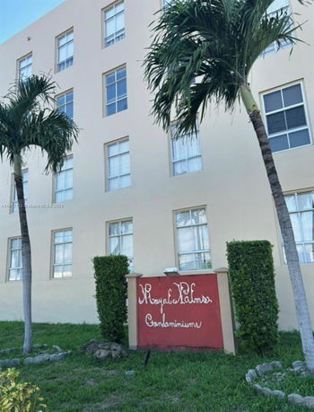 Front view of a condominium building with palm trees.