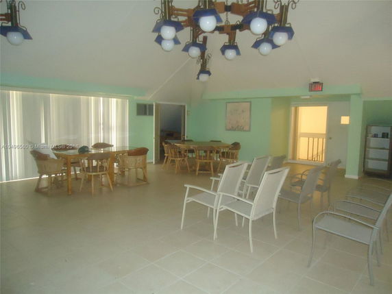Indoor recreational area with tables, chairs, and ceiling chandeliers.