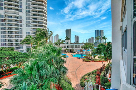 View of surrounding apartment buildings and swimming pool area with palm trees.