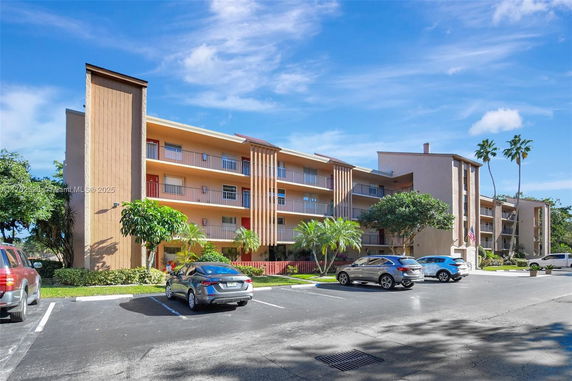 Front view of a multi-story residential building with parking area.
