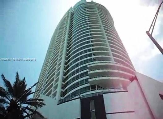 Front view of a tall, multi-story building with a curved facade and numerous balconies.