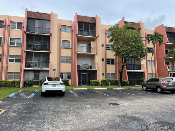 Front view of a multi-story apartment building with balconies and pink accents.