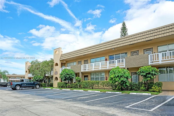 Front view of a two-story residential building with balconies and parking spaces.