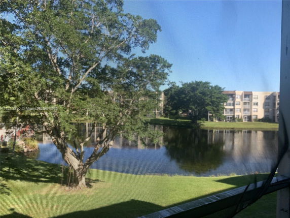 View of a pond and apartment buildings with trees surrounding the area.