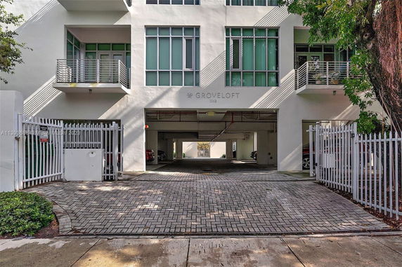 Front view of a multi-story residential building with balconies and a gated entrance.