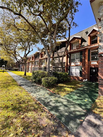 Front view of a multi-story residential building with a path and trees.