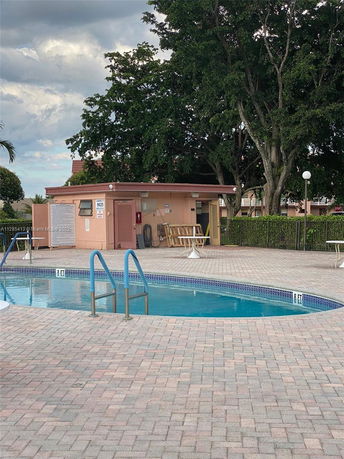 Outdoor swimming pool area with a surrounding concrete deck and a small utility building nearby.