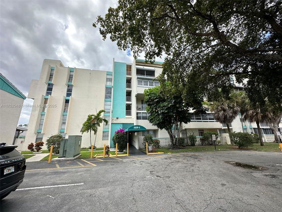 Front view of a multi-story apartment building with balconies and green awnings.