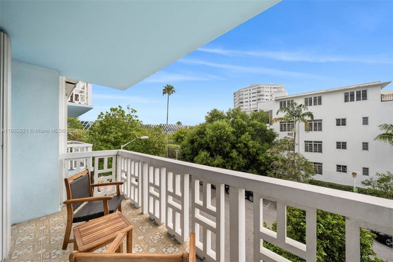 Balcony view with chairs and a distant view of buildings and trees.
