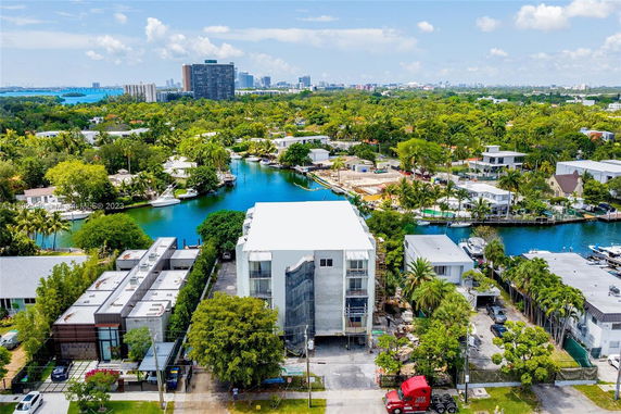 Aerial view of residential area with a waterway surrounded by greenery and buildings.