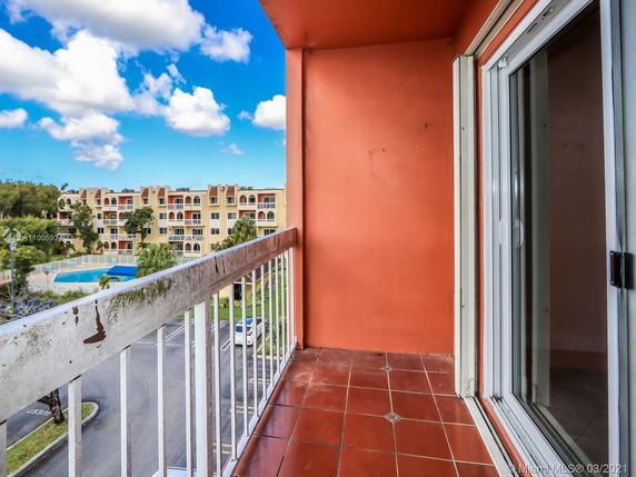 Balcony view overlooking residential buildings with balconies and a swimming pool.