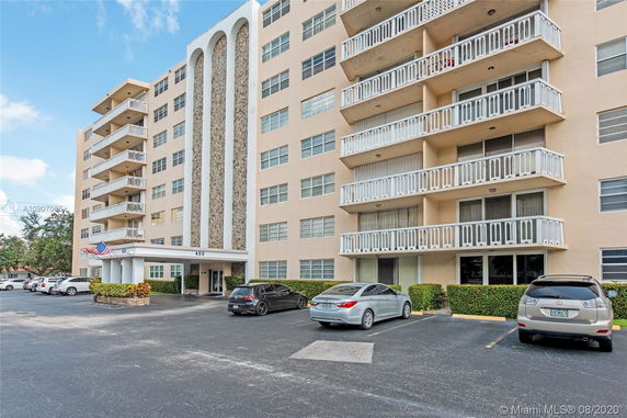 Front view of a multi-story apartment building with balconies and parking area.