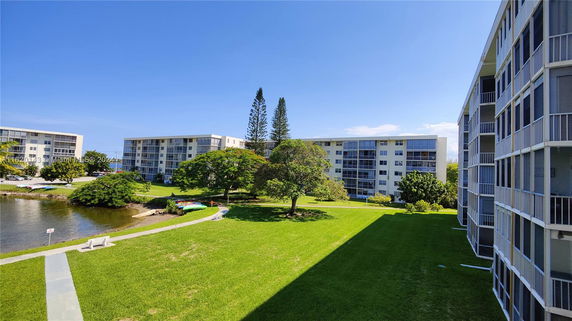 Surrounding view of apartment buildings with a grassy area and a small pond.