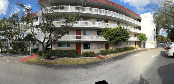 Front view of a multi-story residential building with balconies and red doors.