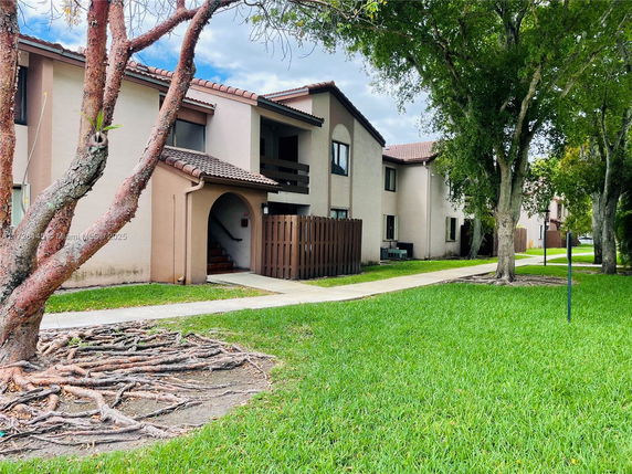 Front view of a two-story residential building with brown roof tiles and an arched entrance.