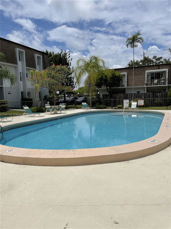 Outdoor swimming pool area surrounded by trees and residential buildings.