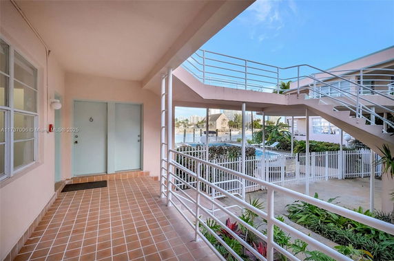 Outdoor view from a building walkway with railings and stairs, showing surrounding area and nearby structures.