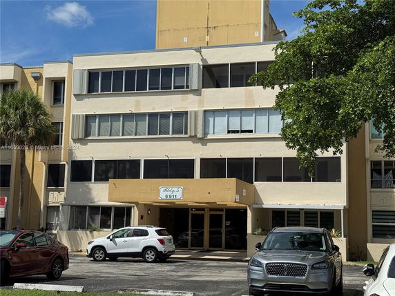 Front view of a multi-story building with parking area in front.