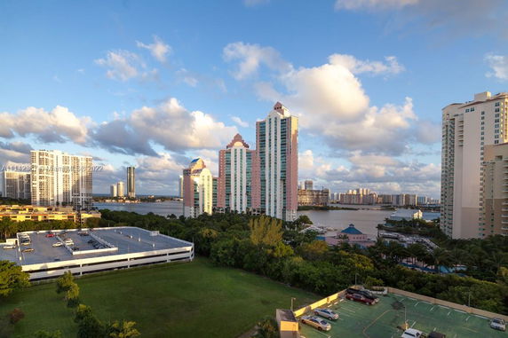 Several high-rise buildings with some taller structures and a view of a water body in the background.