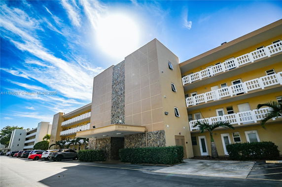 Front view of a multi-story building with balconies and parking area.