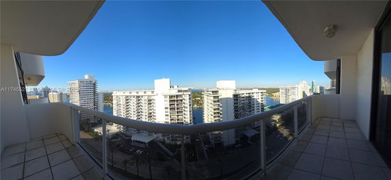 Panoramic view from a balcony overlooking several tall residential buildings and a body of water.