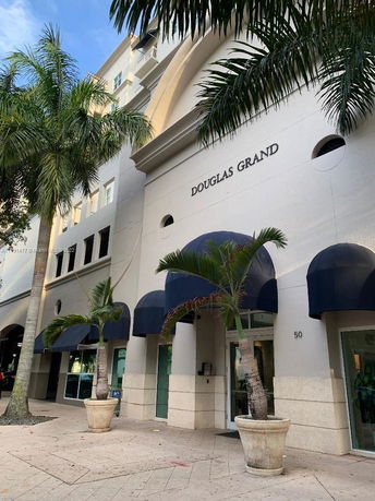 Front view of a multi-story building with arched entrances and blue awnings.