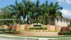 Front view of a multi-story building with palm trees and a sign in front.