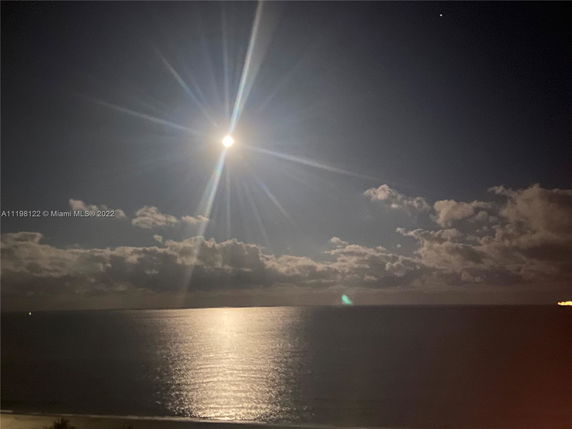 Nighttime panoramic view of the ocean under a bright moon.