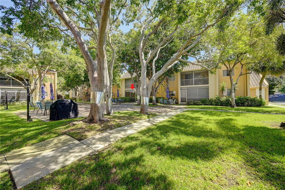 Outdoor area with trees and patio furniture in front of a two-story house.