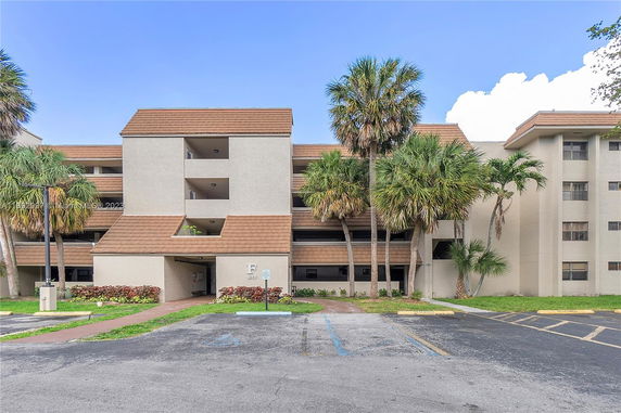 Front view of a multi-story building with balconies and a brown roof.