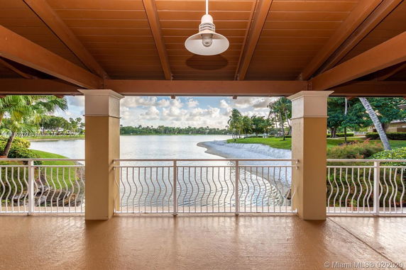 Panoramic view of a serene lake from a covered patio with a railing.