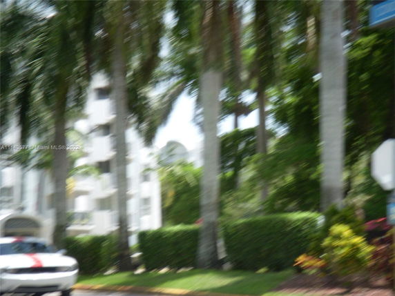 Blurred view of a residential building with palm trees in the foreground.