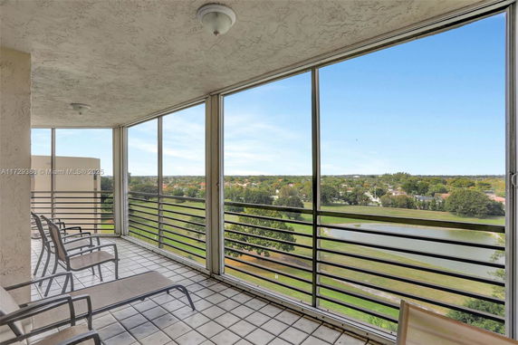 Balcony with lounge chairs overlooking a scenic view of greenery and water.